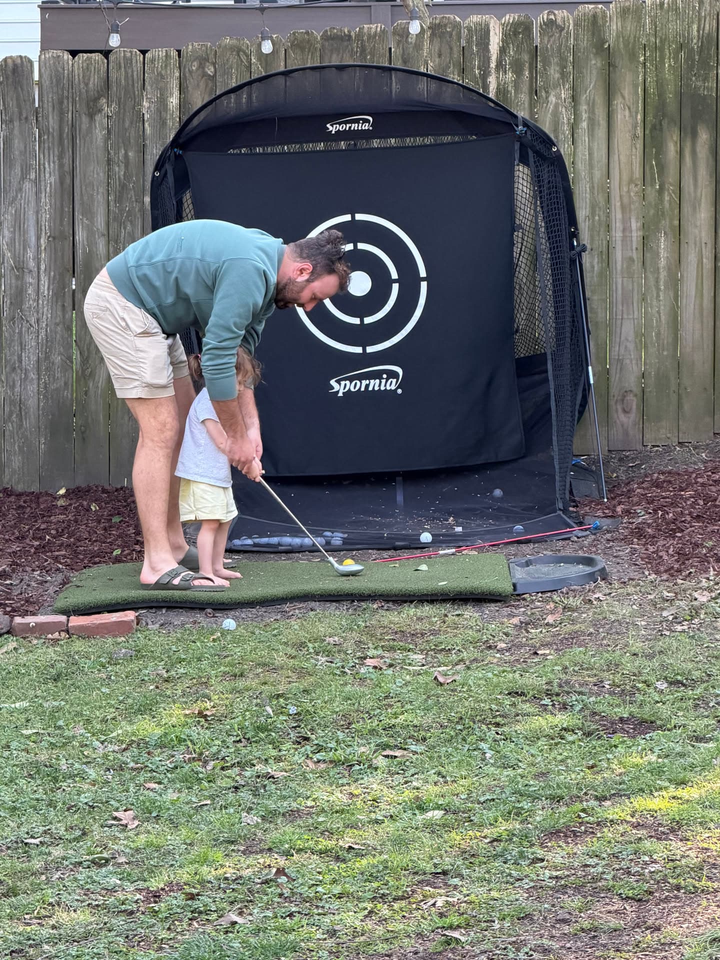 Zakk helping his daughter practice golf in the backyard